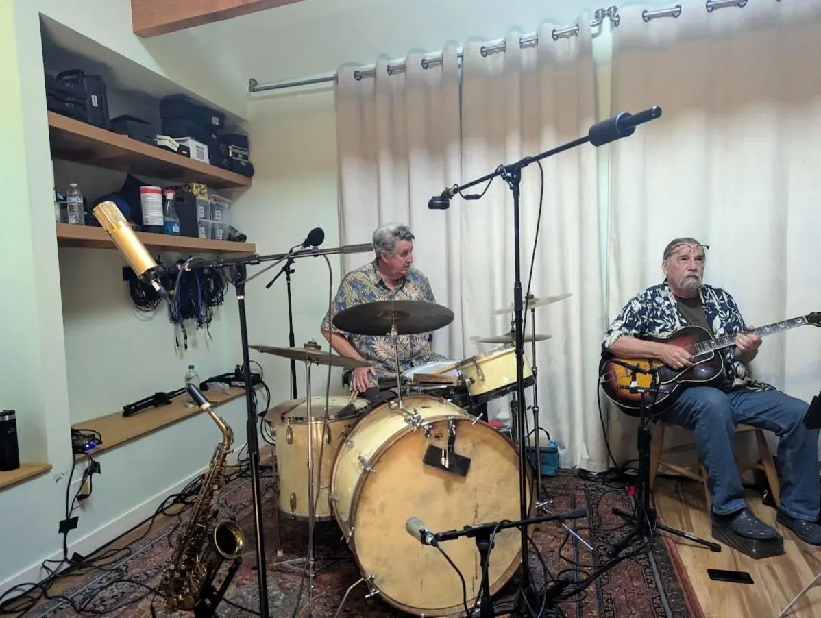Drummer and archtop guitarist playing in the live room, saxophone on a stand in front