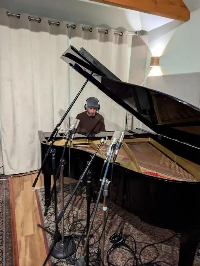 Pianist in headphones at the grand piano through a row of mic stands
