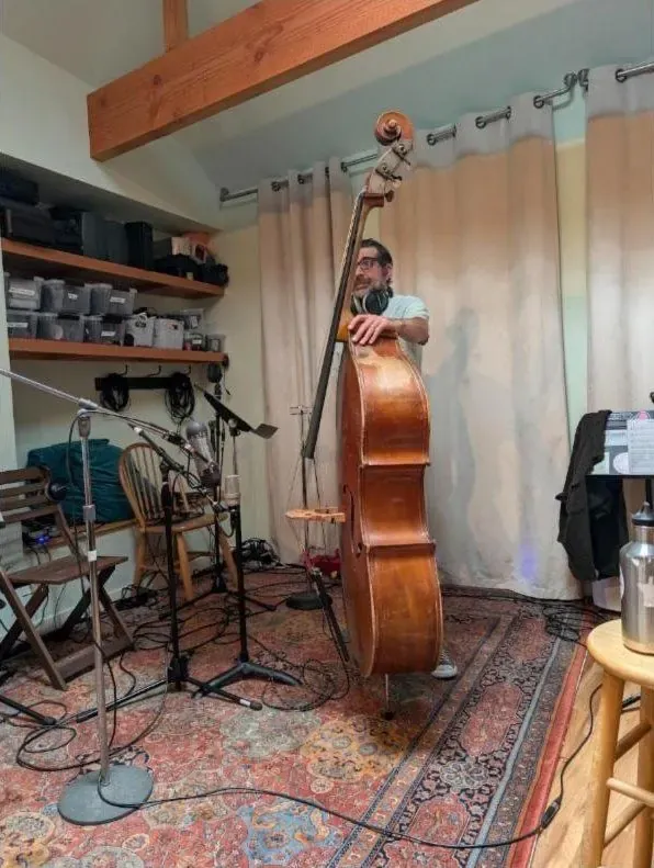 Bassist standing with an upright bass in the live room