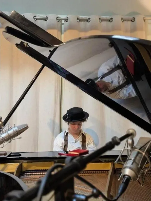 Pianist seen past a condenser mic and boom inside the grand piano