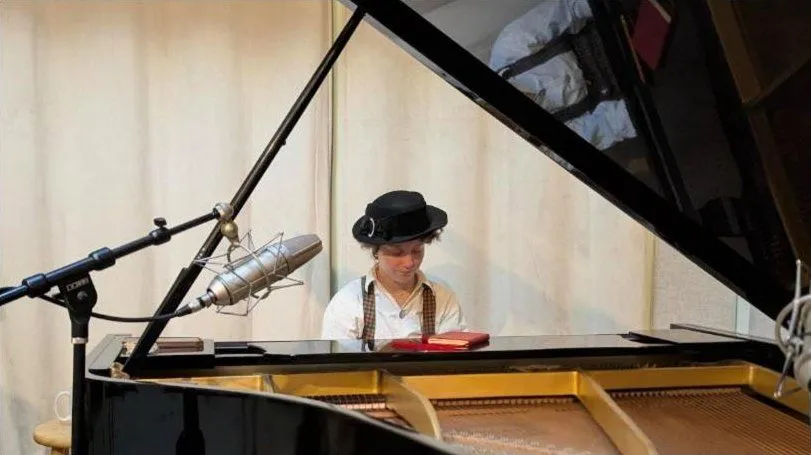 Pianist in a black hat at the grand piano, a large condenser mic in front