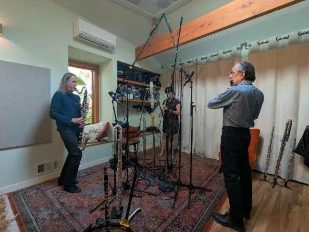 Three woodwind players standing at mics around the live room